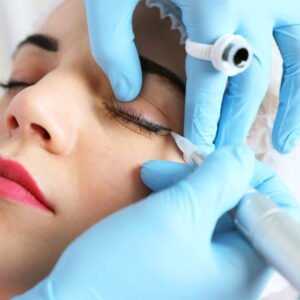 Cosmetologist applying permanent make up on eyes, close-up